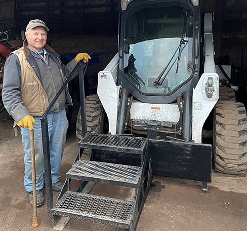 Scott Cebery uses steps and a handrail provided by DVR to safely board his Bobcat loader.