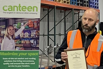 Canteen employee receiving award while standing in warehouse