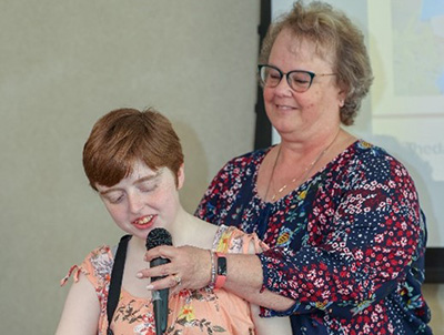Kaylie Cavil, who is blind, reads remarks she prepared detailing her experiences during the internship.Her grandmother holds the microphone for her so Cavil can use both hands to read from her portable brail display.