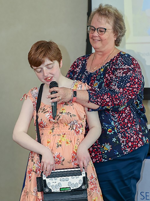 Kaylie Cavil, who is blind, reads remarks she prepared detailing her experiences during the internship. Her grandmother holds the microphone for her so Cavil can use both hands to read from her portable brail display.
